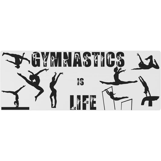 This Gymnastics is Life Yoga mat is white, and features black silhouettes of talented gymnasts across the front, along with the phrase "Gymnastics is Life" in a fun black gymnastics font