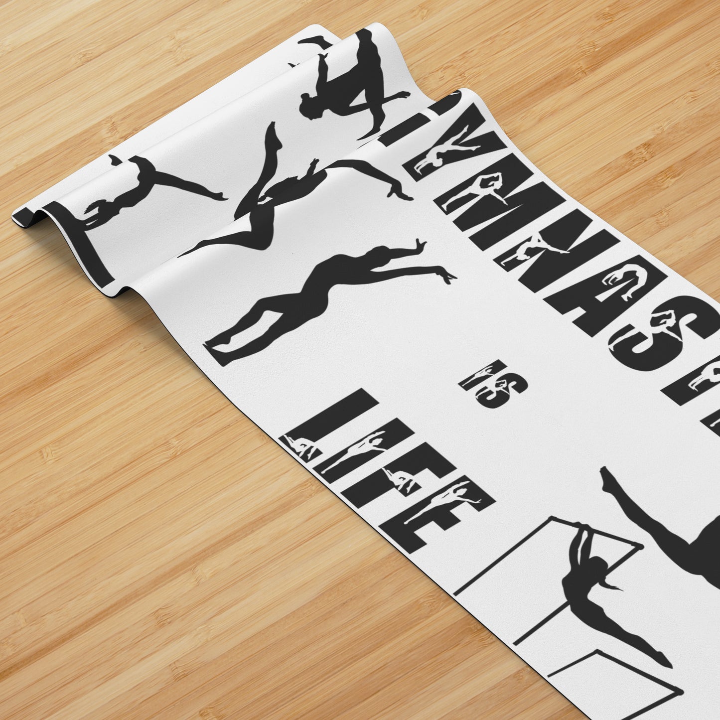 This Gymnastics is Life Yoga mat is white, and features black silhouettes of talented gymnasts across the front, along with the phrase "Gymnastics is Life" in a fun black gymnastics font