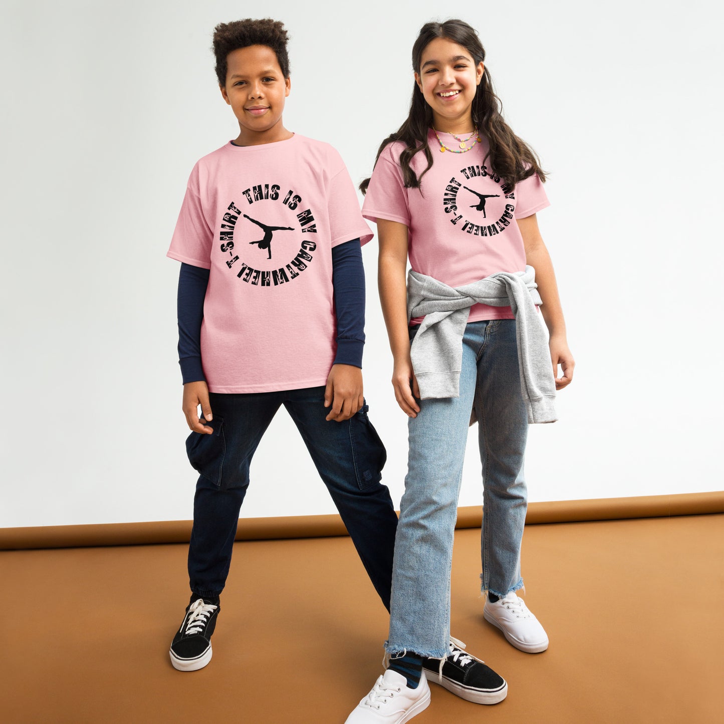 Kids gymnastics T-shirt in pink with black gymnast graphic and ring text.
