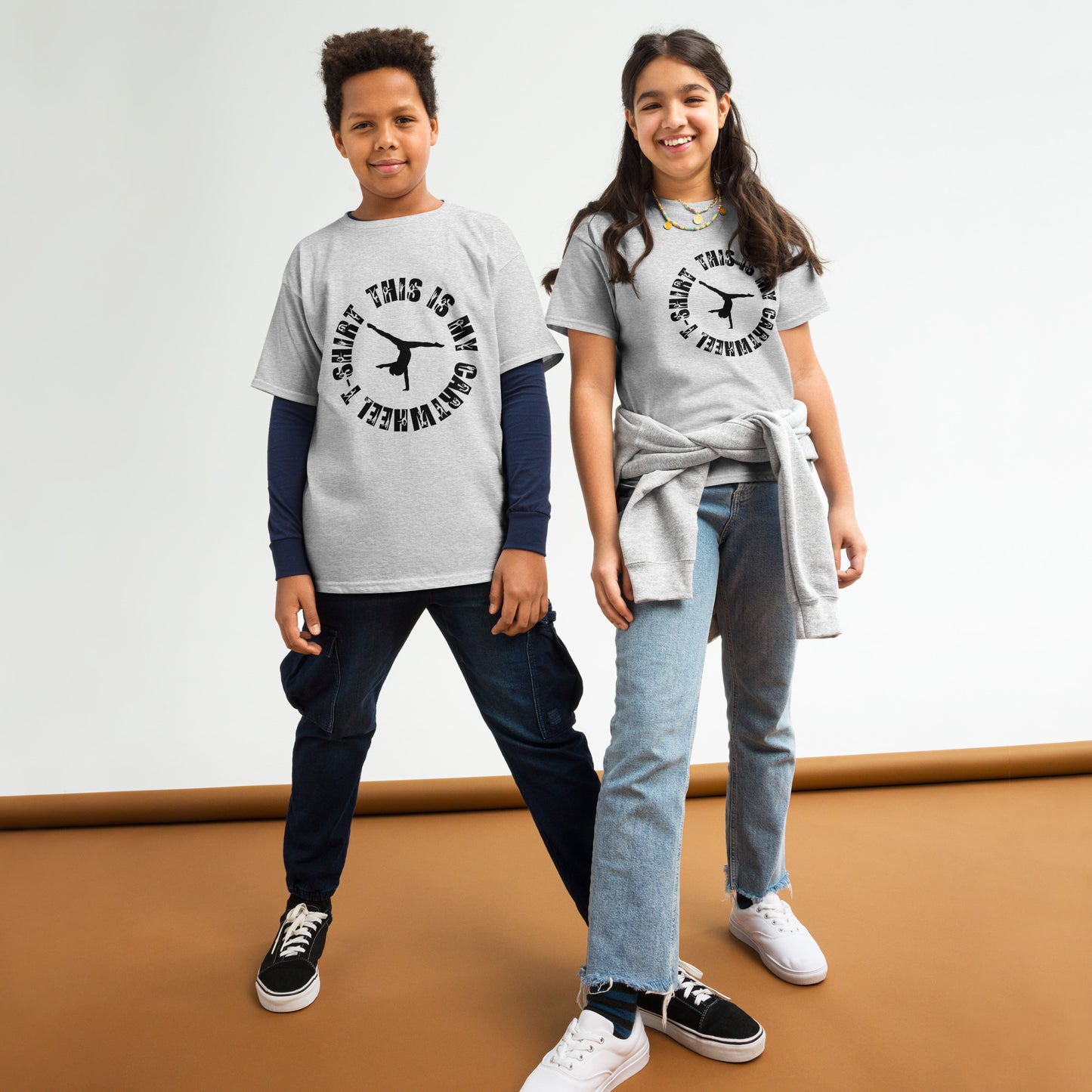 Kids gymnastics T-shirt in light gray with black gymnast graphic and ring text.